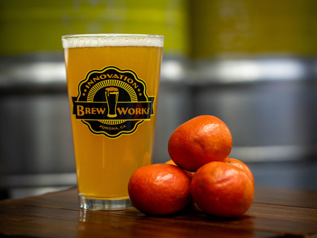 beer in a glass next to a pile of oranges