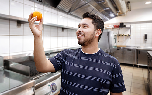 Kitchen staff holding an orange